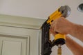 Carpenter brad using nail gun to Crown Moulding on kitchen cabinets framing trim, Royalty Free Stock Photo