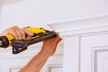 Carpenter brad using nail gun to Crown Moulding on kitchen cabinets framing trim,