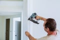 Carpenter brad using nail gun to moldings on doors, that all power tools have on them shown illustrating safety concept