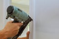 Carpenter brad using nail gun to moldings on doors,