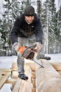 Carpenter builds wooden house made of logs, using chainsaw.