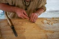 Carpenter carving wood with chisel at medival festival - close up