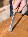 Carpenter with chisel in the hands on the workbench in carpentry, close up carpenter`s hands that work with cutter