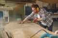 Carpenter is cleaning saw from sawdust with air compressor working in carpentry workshop