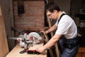 Carpenter cuts a piece of plywood with a miter saw Royalty Free Stock Photo