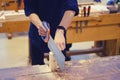 Carpenter cuts a wooden block with a hand saw, close-up