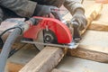 Carpenter cuts wooden board with hand-held circular saw