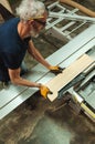 Carpenter cutting a piece of wood on the electric saw cutting machine in a wood workshop Royalty Free Stock Photo