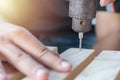 Carpenter drill a wooden board with an electric drill