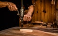 Carpenter drilling a wooden plank with an ancient mechanical hand drill in atelier, closeup.