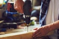 Carpenter drills a hole with an electric drill into a wooden board