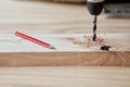 Carpenter drills a hole with an electrical drill