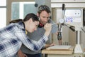 carpenter explaining apprentice how to use drill press machine Royalty Free Stock Photo