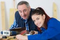 carpenter with female apprentice planing wood in workshop