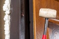 The carpenter, after foaming and insulating the front door, knocks with a hammer for good adhesion of the foam to the wall and Royalty Free Stock Photo