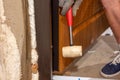 The carpenter, after foaming and insulating the front door, knocks with a hammer for good adhesion of the foam to the wall and Royalty Free Stock Photo