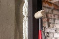 The carpenter, after foaming and insulating the front door, knocks with a hammer for good adhesion of the foam to the wall and Royalty Free Stock Photo