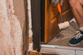 The carpenter, after foaming and insulating the front door, knocks with a hammer for good adhesion of the foam to the wall and Royalty Free Stock Photo
