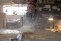 Carpenter girl works on a saw and saws a wooden product Royalty Free Stock Photo