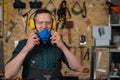 A carpenter in goggles and earmuffs removes a protective respirator.