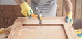 Carpenter with hammer hitting nail on wooden plank