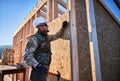 Carpenter hammering nail into OSB panel while building wooden frame house. Royalty Free Stock Photo