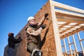 Carpenter hammering nail into OSB panel while building wooden frame house. Royalty Free Stock Photo