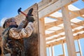 Carpenter hammering nail into OSB panel while building wooden frame house. Royalty Free Stock Photo