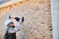 Carpenter hammering nail into OSB panel while building wooden frame house. Royalty Free Stock Photo