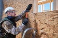 Carpenter hammering nail into OSB panel while building wooden frame house. Royalty Free Stock Photo