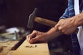 Carpenter hammering a nail into wooden plank