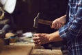 Carpenter hammering a nail into wooden plank