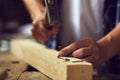 Carpenter hammering a nail into wooden plank in his workshop