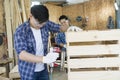 Carpenter hammering nails into wood with a automatic nailer. Carpenter worker with machine at wood workshop