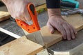 Carpenter hand with handsaw cutting wooden boards.