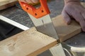 Carpenter hand with handsaw cutting wooden boards. Carpentry, construction.