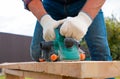 Carpenter hands in gloves electric plane planing lumber, flying shavings, sawdust. Close-up on gloved hands with an electric plane Royalty Free Stock Photo