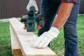 Carpenter hands in gloves electric plane planing lumber, flying shavings, sawdust. Close-up on gloved hands with an electric plane Royalty Free Stock Photo