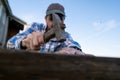 Carpenter hands make a bench by hammering nails into a plank in a village yard against a blue sky. Royalty Free Stock Photo