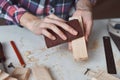 Carpenter hands polishing wooden planks with a sandpaper. Concept of DIY woodwork and furniture making Royalty Free Stock Photo