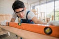 Carpenter handsome man wearing goggle and gloves with using water level for height checking of desk in workplace at home Royalty Free Stock Photo