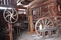 Carpenter historical workplace with some wooden wagon wheels, vertical stand saw, various scales and other tools.