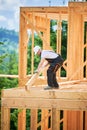 Carpenter holding large beam while builds wooden frame house near the forest. Royalty Free Stock Photo