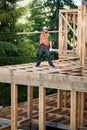 Carpenter holding large beam while builds wooden frame house near the forest. Royalty Free Stock Photo