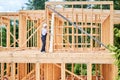 Carpenter holding large beam while builds wooden frame house near the forest. Royalty Free Stock Photo