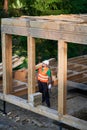 Carpenter holding large beam while builds wooden frame house near the forest. Royalty Free Stock Photo