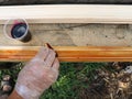 a carpenter impregnates a wooden fillet with a dark solution