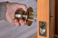 Handyman pushes the door knob spindle through the face bore and the latch assembly