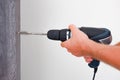 A carpenter is installing a doorknob with a latch on a wooden door. Close-up of a hand with a tool