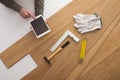 Carpenter installing a wooden floring and using a tablet